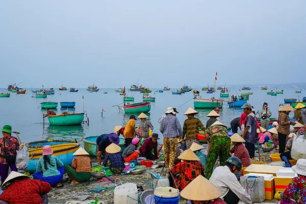Mui Ne, Vietnam- 22 Mart 2025: Sabah erken saatlerde yerel halk yeni avlarla dönen yuvarlak botlarla sahil pazarında toplanıyor.