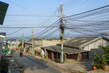 Mui Ne, Vietnam- 22 Mart 2025: Mui Ne 'de denize açılan dar bir ara sokak, evler, saksılar ve karışık tellerle çevrili bir labirent.