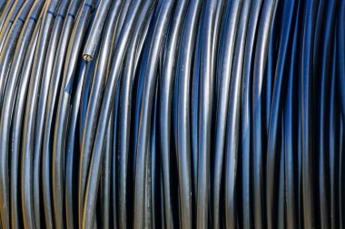 İnşaat projelerinde elektrik veya veri kurulumu için kullanılan bir varilin üzerine sıkıca sarılmış siyah kablo demetinin ayrıntılı görüntüsü