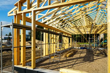 Görünür kirişleri, iskelesi ve kumlu bir alanda merdivenleri olan ahşap çerçeve inşaatı. Modern çevre dostu bina devam ediyor