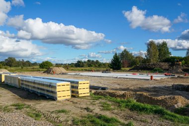 İnşaat alanındaki temel levha ve paketlenmiş sandviç panelleri. Endüstriyel kalkınma projesi için hazırlanmış yapı malzemeleri