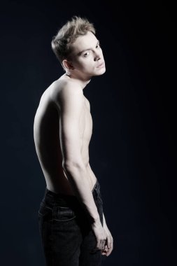 İnsanlar ve duygular. Kotlu ve çıplak gövdeli genç bir adamın portresi. Stüdyoda siyah bir arka planda negatif duygularla poz veriyor..