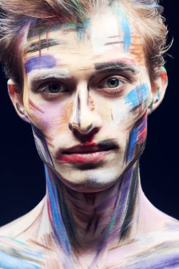 Vücut boyama projesi. Siyah arka planda renkli yüzü olan yakışıklı bir adamın portresi. Sanat ve moda.