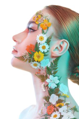 Çekici kızıl saçlı, zarif makyajlı ve yüzünde ve omzunda yaz çiçekleri olan bir kızın yakın çekimi. Beyaz arka plan. Kozmetik ve parfüm. Yazın kokusu..