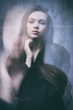 Güzellik, insanlar, duygular. Uzun kahverengi saçlı ve siyah gömlekli güzel bir kızın portresi. Sakince ve düşünceli bir şekilde kameraya bakıyor.. 