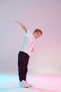 Modern dans stili. Stüdyoda dans eden havalı break dansçı çocuk beyaz arka planda karışık renkli ışıkta dans ediyor. Hip-hop dansçısı. Spor ve aktiviteler.