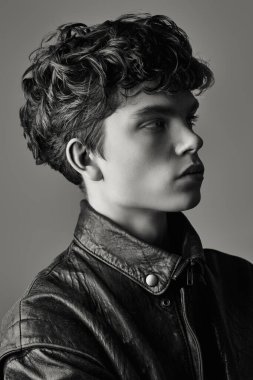 Deri ceketli yakışıklı bir gencin stüdyo portresi. Siyah ve beyaz atış. Erkeklerin gençlik modası. 