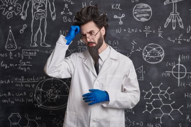 Zeki bir profesör, yeni bir bilimsel problemi nasıl çözeceğine dair hiçbir fikri olmayan üzgün ve kafa karıştırıcı bir ifadeyle bilimsel formüller ve diyagramlarla tahtada duruyor..