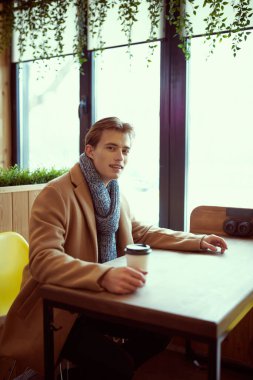 Soğuk bir kış gününde sıcacık bir kafede sıcak kahve içen şık, sarışın, şık bir adamın portresi. İnsan konsepti, yaşam tarzı.
