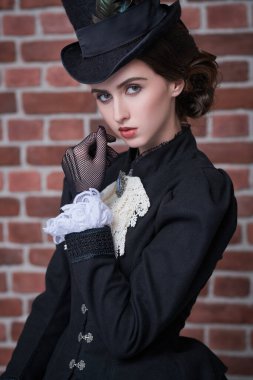 Viktorya döneminin makyaj ve saç stiliyle geleneksel 19. yüzyıl giysileri içinde zarif esmer bir kadının portresi. Tuğla duvar arka planı. Tarihsel saç stili ve makyaj.