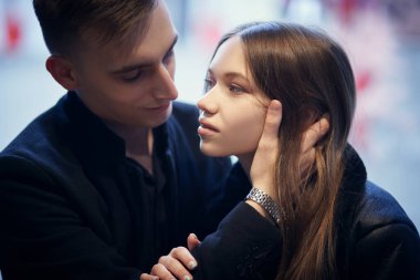 Yakışıklı bir genç adam ve güzel bir kız şefkatle sarılıp birbirlerinin gözlerinin içine bakarlar. Aşk konsepti.