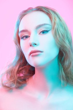 Stüdyoda pembe arka planda duran zarif makyajlı, kızıl saçlı çekici bir kızın portresi. Kadın güzelliği ve sağlığı. Kozmetik ve cilt bakımı. Güzel atış.. 