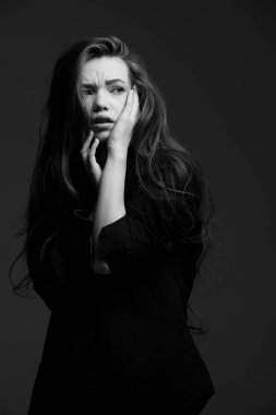 Uzun kahverengi saçlı, siyah gömlekli, endişeyle ve endişeyle korkuyla uzaklaşan güzel bir genç kızın siyah beyaz portresi. Psikolojik portre. 