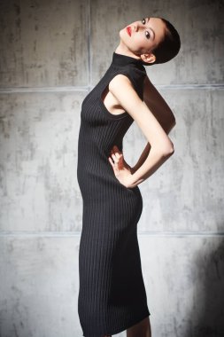 Gece makyajlı zarif bir kızın moda portresi grunge arka planda siyah örülmüş bir beden giysisi ile poz veriyor. Kadınlar için şık moda..