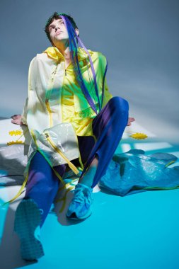 Yaratıcı tasarımcı kıyafetleri. Yerde poz veren şık tasarımcı elbiseli yakışıklı bir erkek modelin portresi. Stüdyo portresi. Yüksek moda çekim. 