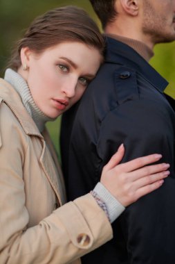 Aşık insanlar. Güzel bir genç kadının portresi şık kıyafetler içinde sevdiğine arkadan sarılıyor.. 