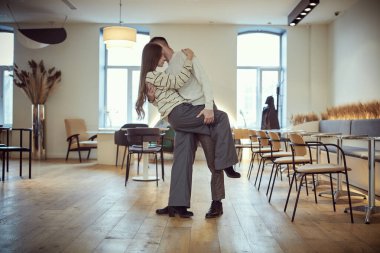 Birbirine aşık genç bir çiftin günlük kıyafetlerini giyip bir kafede tutkuyla dans edişinin uzun bir görüntüsü. Gençler, ilişki ve yaşam tarzı. Aşık mutlu çift.