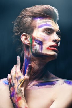 Siyah bir arka planda, renkli tenli yakışıklı bir sarışının portresi. Sanat, moda ve vücut boyası.