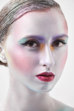 Gümüş yüzlü, vücutlu ve beyaz arka planda renkli makyajlı genç bir kadının güzel bir fotoğrafı. Vücut boyama, vücut sanatları. Güzellik ve kozmetik konsepti. 
