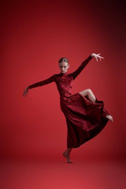 Dans ifadesi. Muhteşem balerin kız kırmızı kadife bir elbiseyle stüdyoda dans ediyor..