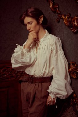 Yakışıklı bir elf çocuğu düşünceli bir şekilde sihirli kalesinde duruyor. Fantezi. Peri masalı, sihir. 