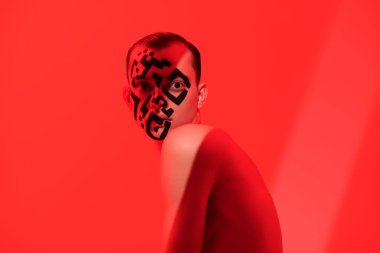 Coronavirus aşısı. Yüzüne parlak kırmızı bir zemin üzerine çıplak bir gövde ve QR kodu çizilmiş genç bir adamın sanat portresi. İnsanların küresel veritabanları, bir kişi üzerinde kontrol.