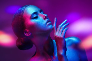 Vücut boyama. Güzel, kadınsı bir modelin sanat portresi. Mor bir arka planda parlak, parlak, neon renkli, kırmızı bir teni var. Güzellik ve kozmetik konsepti. 