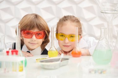 Çocukların erken gelişimi. Gözlüklü iki çocuk laboratuvarda kimyasal deneyler yapıyor. Eğitici kavram. 