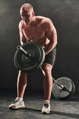 Koyu dumanlı arka planda halterle egzersiz yapan yakışıklı bir adam. Sağlık ve spor konsepti. Ağırlık kaldırma.