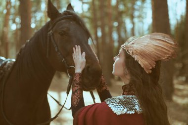 Güzel bir valkyrie ormanda dururken atıyla konuşuyor. İskandinav mitolojisi. Fantezi.