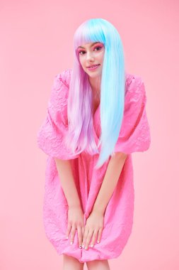 Japon animasyon tarzı. Parlak makyajlı, menekşe mavisi peruklu, şık pembe elbiseli güzel bir kız. Pembe arka planda stüdyo portresi. Moda. Saç stili, saç rengi, makyaj..