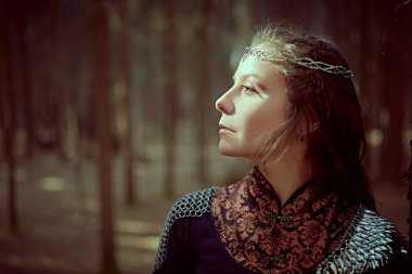 Güzel bir ortaçağ kraliçesi, sık bir ormanda yüzüne düşen bir güneş ışığıyla duruyor. Eski efsaneler. Hayal dünyası..