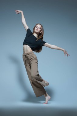 Çağdaş bale. Modern balerin stüdyoda gri arka planda artistik bir şekilde dans eder. Dans ifadesi. Tam boy portre.