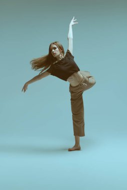 Çağdaş bale. Modern balerin stüdyoda gri arka planda artistik bir şekilde dans eder. Dans ifadesi. Tam boy portre.