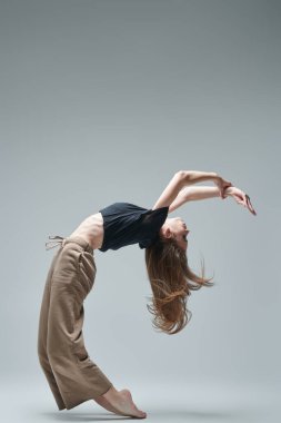 Gri bir stüdyoda modern bir dans sergileyen bir balerin kızı portresi. Çağdaş bale. Tam boy stüdyo resmi. Dans ifadesi. 