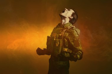 Savaşın yıkıcı gücü. Koruyucu Savaş Üniformalı kızgın asker kırmızı ışık ve dumanla arka planda öfkeyle bağırıyor. Stüdyo çekimi.