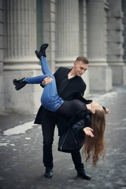Neşeli kış yürüyüşü. Mutlu genç adam bir şehir caddesinde duran güzel kız arkadaşını neşeyle kollarına alır. Gençler ve ilişkiler. Aşk hikayesi.. 