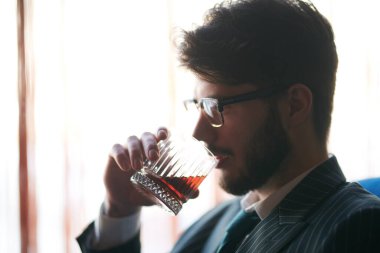 Pahalı takım elbiseli saygıdeğer bir adamın bir bardak viski içerken yan görüntüsü. Lüks bir yaşam tarzı. İş adamı. 