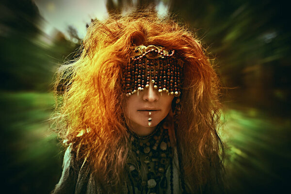 Страшная лесная ведьма в маске, закрывая глаза, стоит посреди леса, исполняя таинственный ритуал. Женщина-шаман. Язычество. Ритуал смерти. Хэллоуин. 