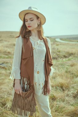 Romantik boho ve hippi tarzı. Boho tarzı kıyafetler ve aksesuarlar içinde güzel bir kız bozkırda duruyor. Yaz modası.