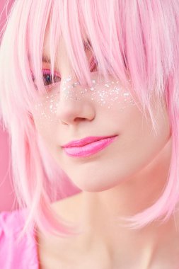 Asya tarzı, anime. Pembe makyajlı ve pembe arka planda pembe perukla poz veren parlak çilli güzel bir kızın portresi.. 