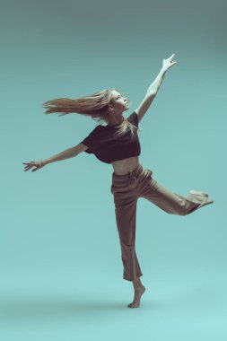 Gri bir stüdyoda modern bir dans sergileyen bir balerin kızı portresi. Çağdaş bale. Tam boy stüdyo resmi. Dans ifadesi. 