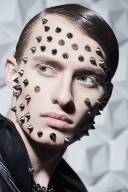 Rock tarzı ve moda. Siyah deri ceketli, beyaz teknoloji arka planında metal çiviler olan vahşi bir gencin portresi..