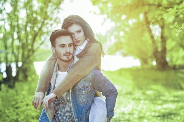 Birbirine aşık gençler. Yaz parkında yürürken güzel kız arkadaşını sırtında taşıyan yakışıklı bir genç. Güneşli yaz günü. 