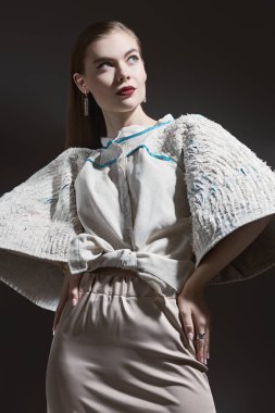 Moda çekimi. Zarif makyajlı, bej bluzlu ve bej düz etekli güzel bir manken. Siyah stüdyo geçmişi.