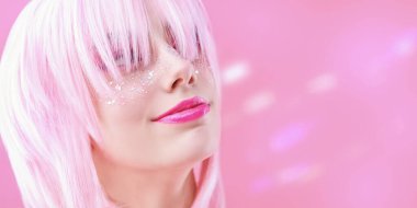 Asya tarzı, anime. Pembe dudaklı, parlak çilli pembe bir arka planda pembe perukla poz veren güzel bir genç kızın portresi. Boşluğu kopyala.
