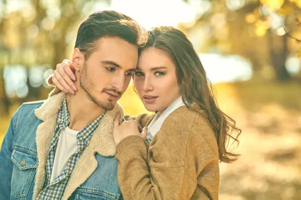 Birbirlerine aşık güzel genç insanlar nehir kıyısında yürürken harika bir sonbahar gününün tadını çıkarıyorlar. Aşk ve ilişki.