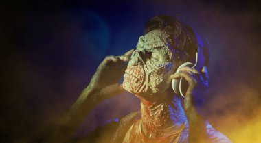 Zombi, müzik aşığı. Korkunç kanlı bir zombi adam kulaklıkla müzik dinliyor, gözlerini kapatıyor. Kıyametten sonraki hayat. Cadılar Bayramı, korku filmi. Boşluğu kopyala.