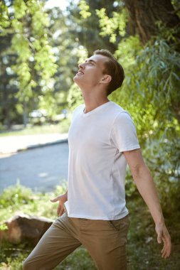 Mutlu insanlar, olumlu duygular, yaşam tarzı. Mutlu bir adam parkta güneşli bir yaz gününün tadını çıkarır..