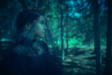 Yas tutan duvak ve siyah elbiseli, ellerini bağlayıp dua eden, karanlık bir saray parkında duran soylu genç bir kadın. 19. yüzyıl. Trajedi, roman. Güzel Kara Kraliçe. Fantezi.
